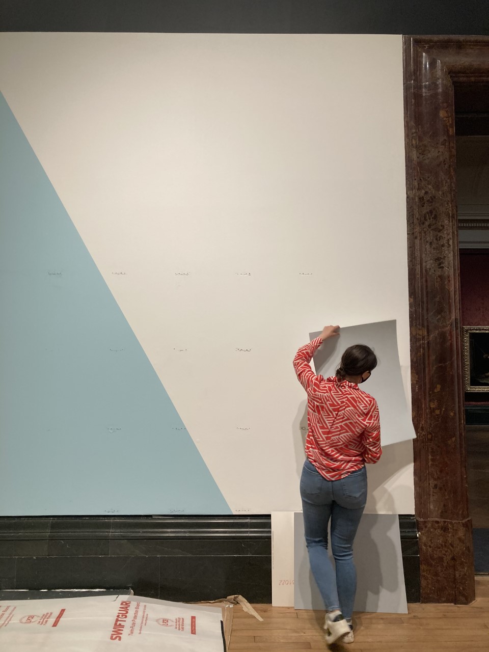 Nicola holding a white piece of paper on wall