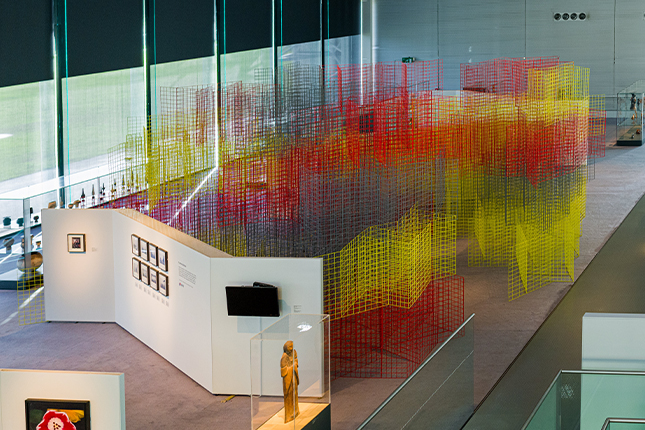 Red, yellow and blue mesh installation in a large airy space