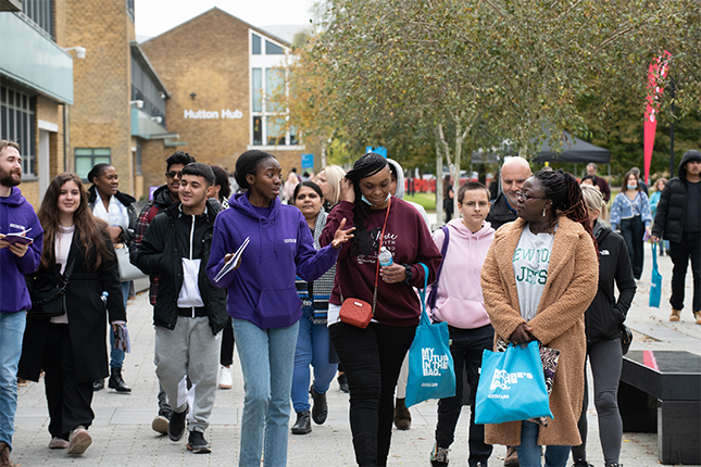 A group of students enjoying Freshers' Fair holding university merchandise and chatting