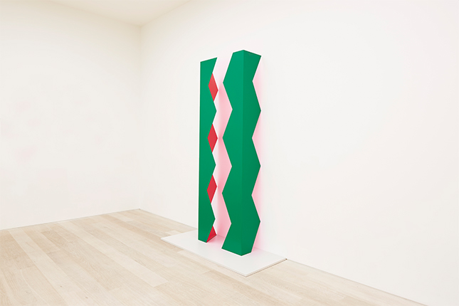 Vertical green, red and light pink zigzag installation in white walled gallery