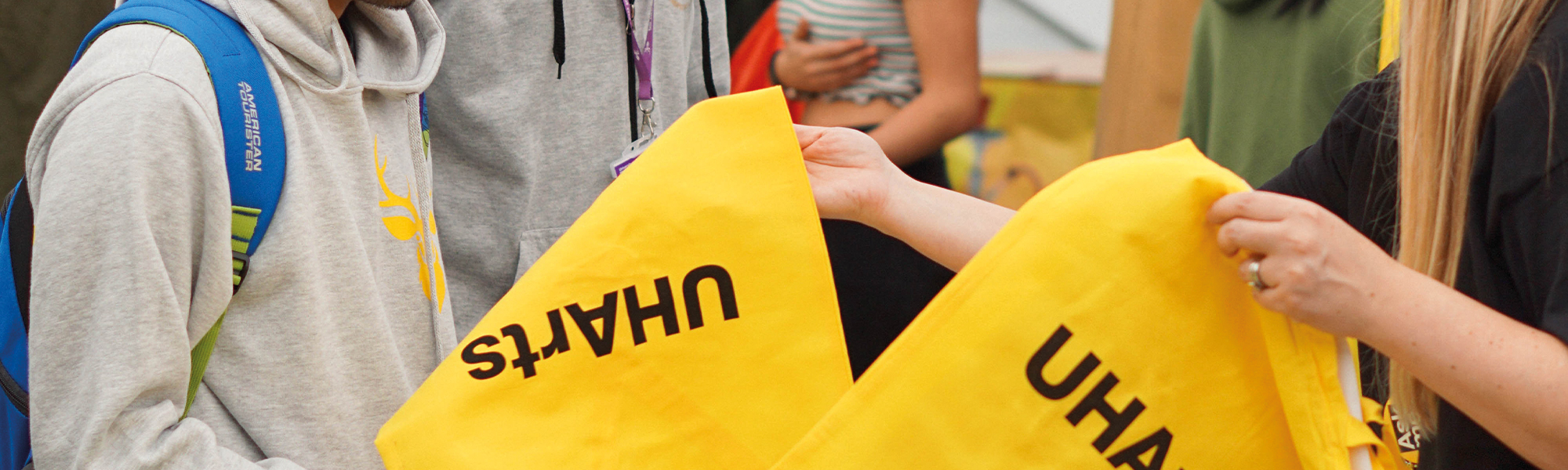 Students handing out yellow UHArts tote bags