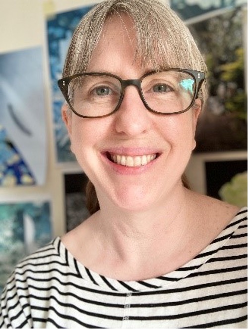 Photograph of Sarah Evans wearing glasses and stripy top, smiling 